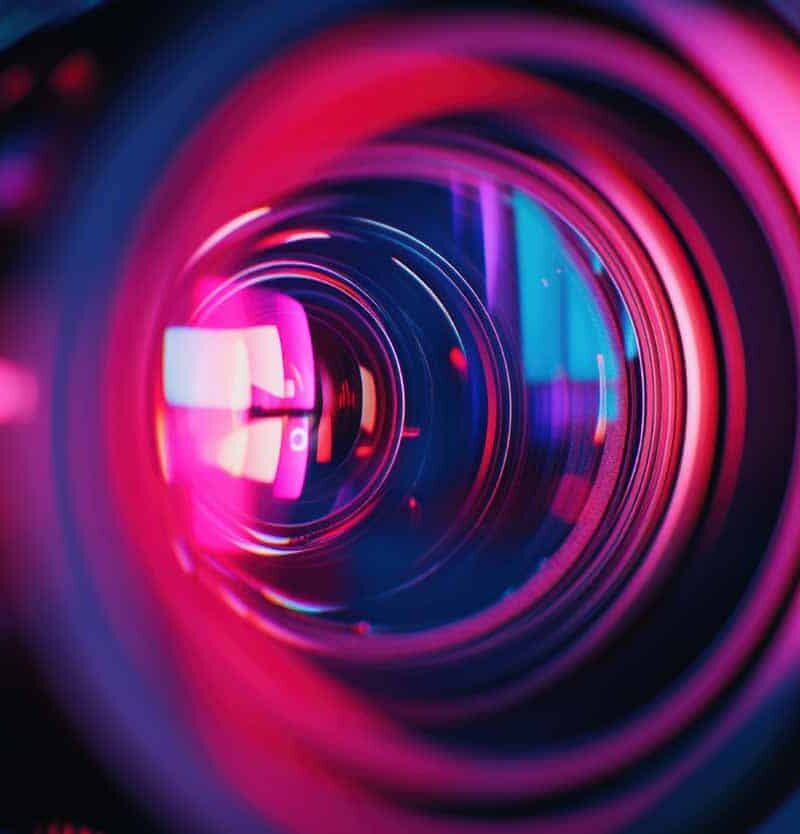 Close-up of a video camera lens, focusing on the red and blue reflections, representing vibrant colors in video production. --ar 67:45 --v 6.1 Job ID: ceaade54-2b58-4d25-8be6-23037b36d2c5